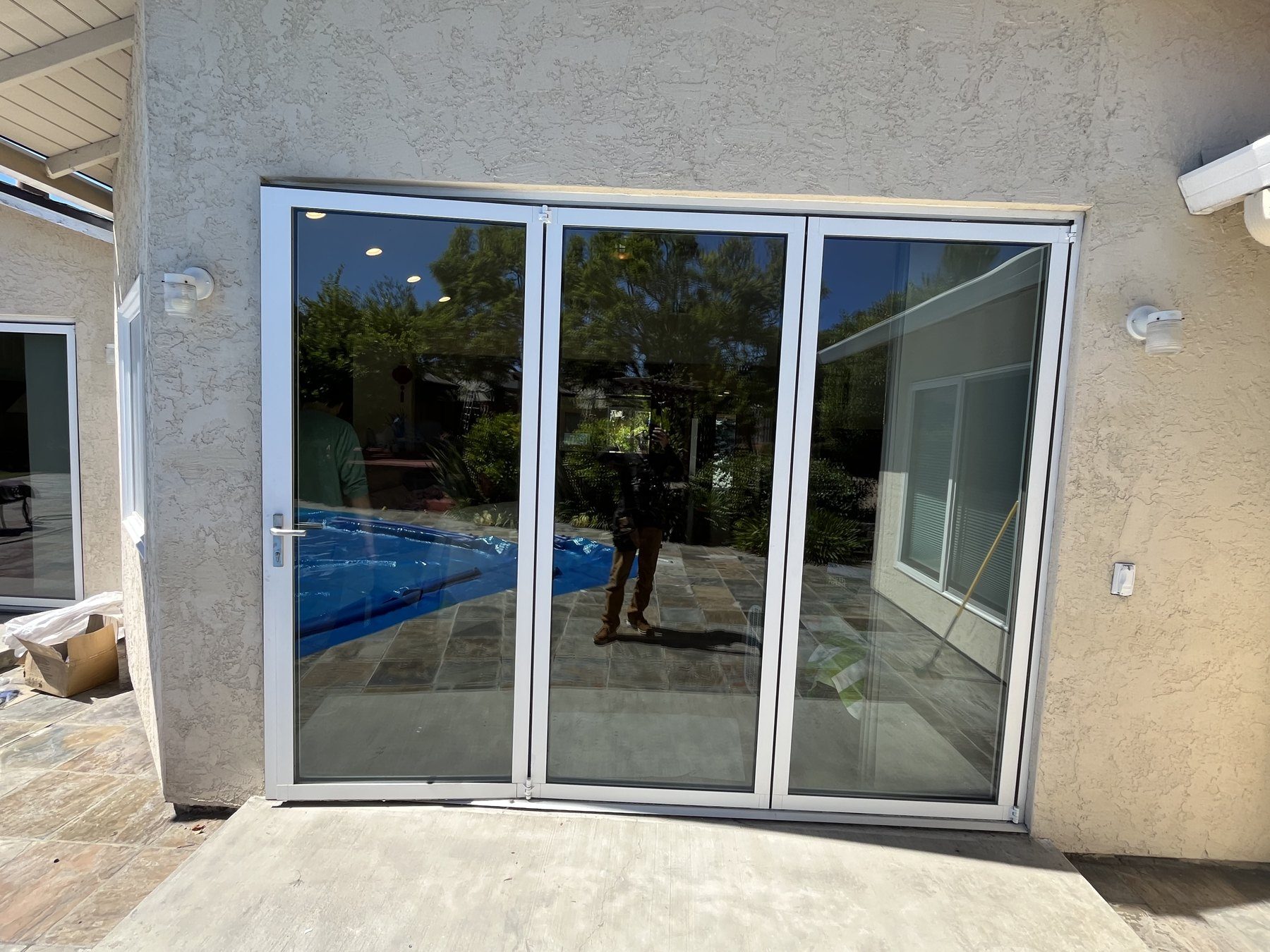 New white bi-fold glass patio door installed on a stucco home