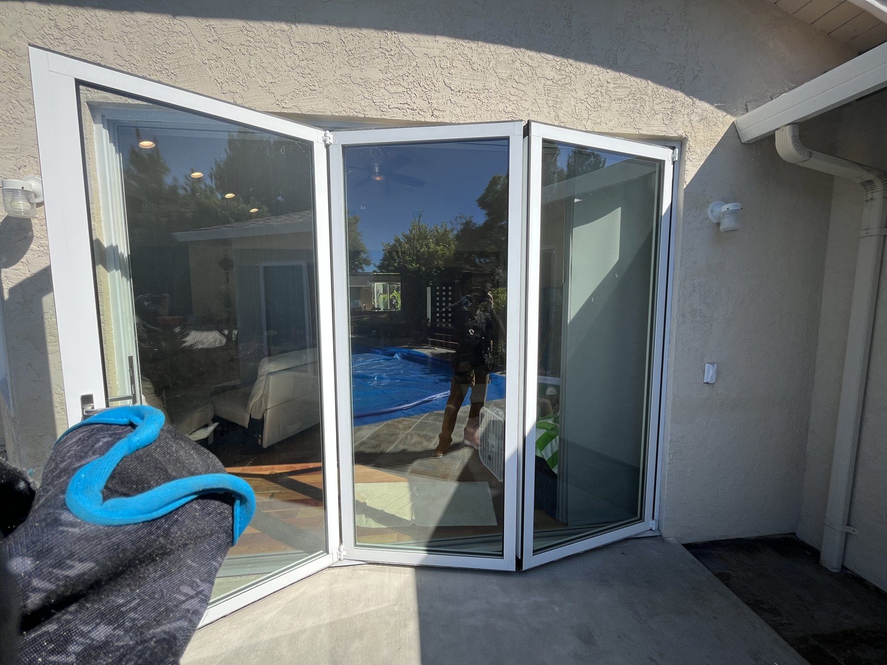 Bi-fold glass patio door folded open onto a backyard patio