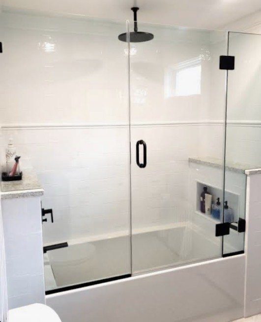 Tub and shower enclosure with black hardware and frameless glass panels
