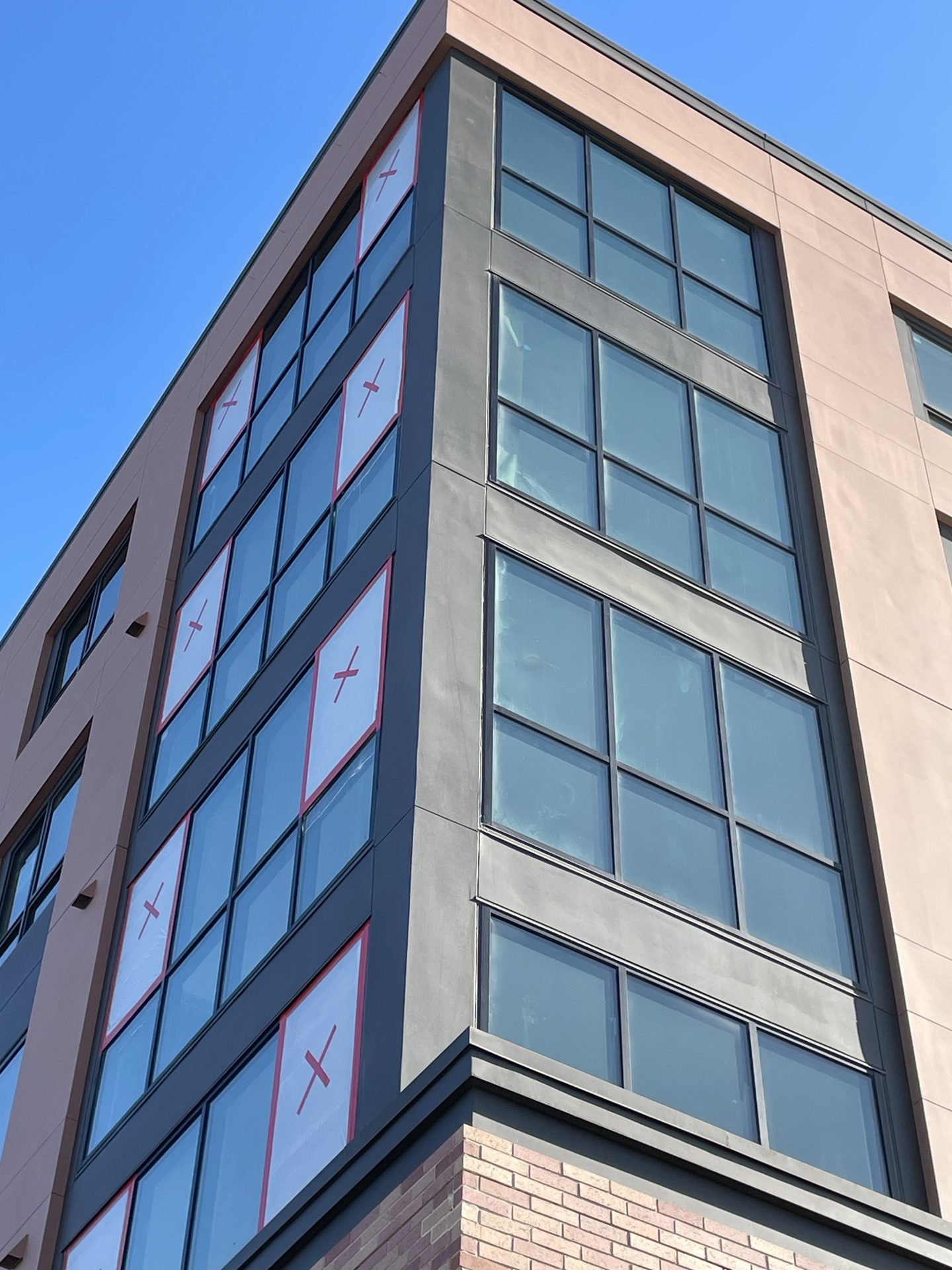 New window replacements marked and installed on a multi-story building